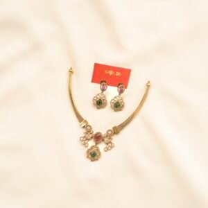 Gold necklace with ruby and emerald drops and matching earrings on cream background – Karra De.