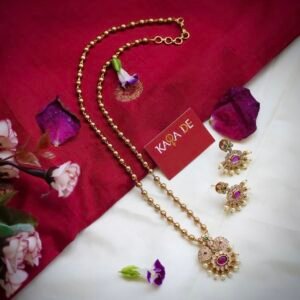Ruby mangal necklace set with gold bead chain and pearl drops on red saree background – Karra De.