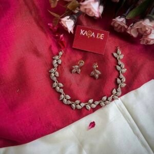 Diamond leaf necklace set with matching earrings on red cloth background – Karra De.