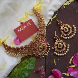 Antique gold goddess temple choker with emerald stones and pearl drops on white silk fabric – Karra De.